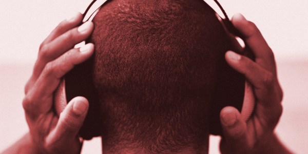 Image shows the back of a man's head wearing headphones as he listens to music to illustrate songs getting stuck in people's heads or the phenomenon known as earworms.