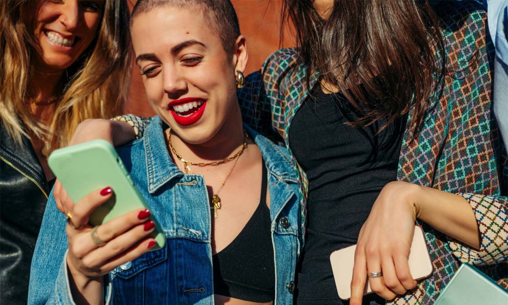 Group of women crowding around a phone.