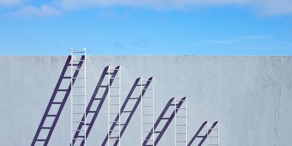 An image showing increasingly small ladders reaching up to the same height to indicate the impact of inflation on wages.